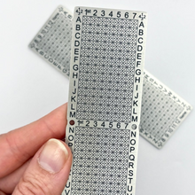 Load image into Gallery viewer, Hand holding a 12-word Standard Punchplate with additional plates in the background.
