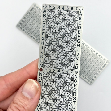 Hand holding a 12-word Standard Punchplate with additional plates in the background.